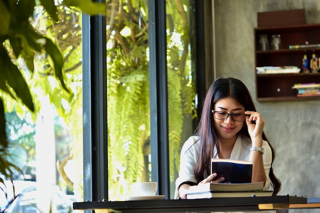 Beautiful woman reads a book in a happy cafe. Ideas for morning education