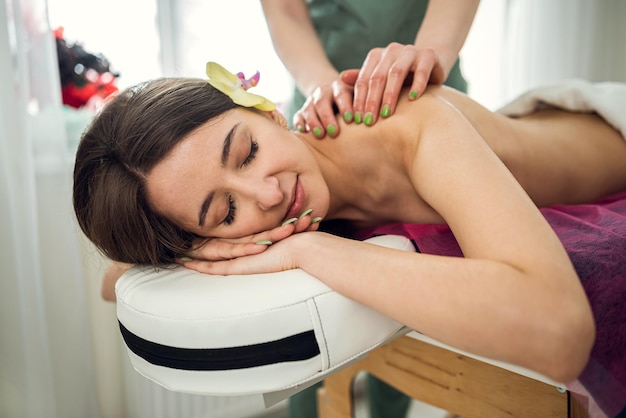 Beautiful woman receive restorative massage on her back in spa salon