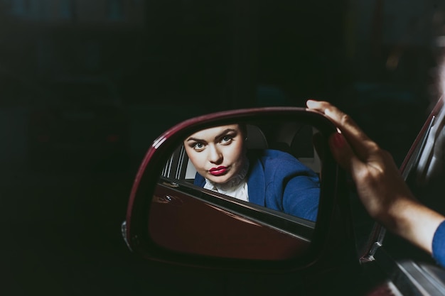 Beautiful woman reflected in mirror of carBeautiful young woman buys a car in the dealership saloon