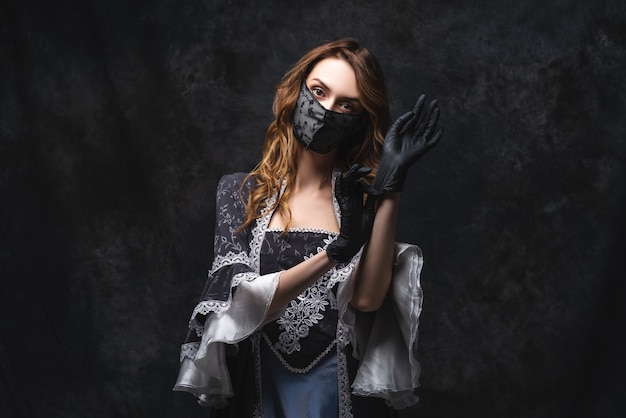 Beautiful woman in renaissance dress, face mask and gloves , coronavirus, covid-19 protection concept.