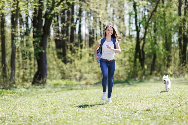 Beautiful woman runs with a dog in a summer park