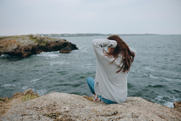 Beautiful woman seated on the coast sweater landscape unaltered