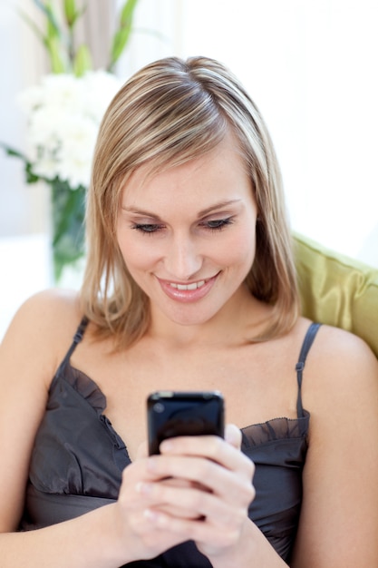 Beautiful woman sending a text sitting on a sofa 