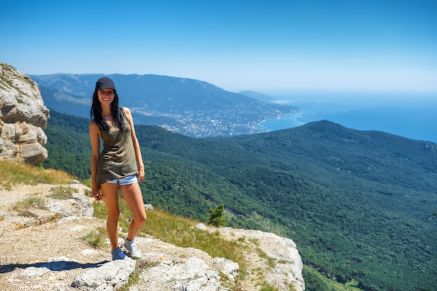 Beautiful woman in shorts standing on a cliff with a beautiful view