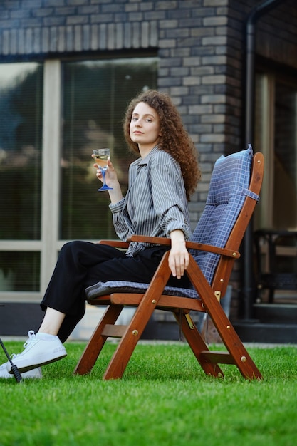 Beautiful woman sits on chair on backyard