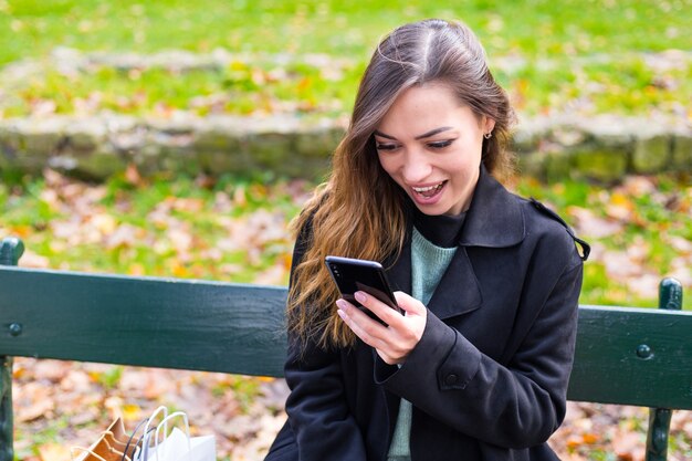 Beautiful woman sitting on a bench using her smartphone