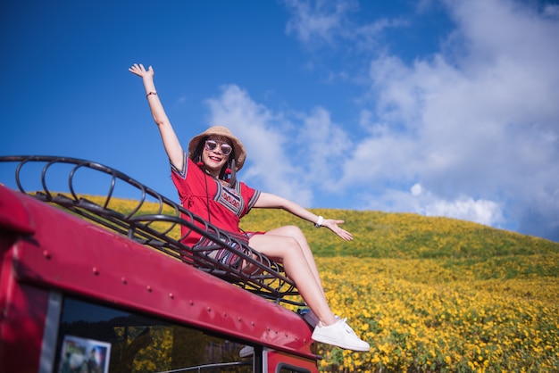 A beautiful woman sitting on a red car roof