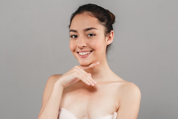 Beautiful woman skincare portrait with hand over gray background. Studio shot.