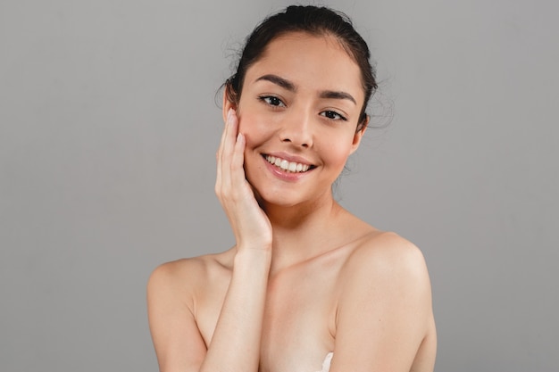 Beautiful woman skincare portrait with hand over gray background. Studio shot.