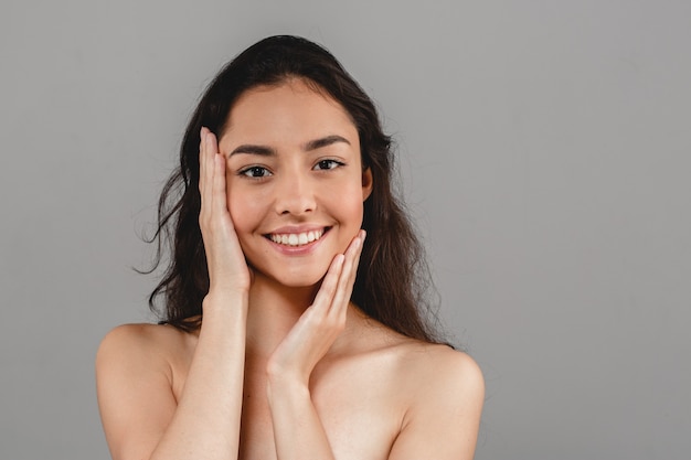 Beautiful woman skincare portrait with hand over gray background. Studio shot.