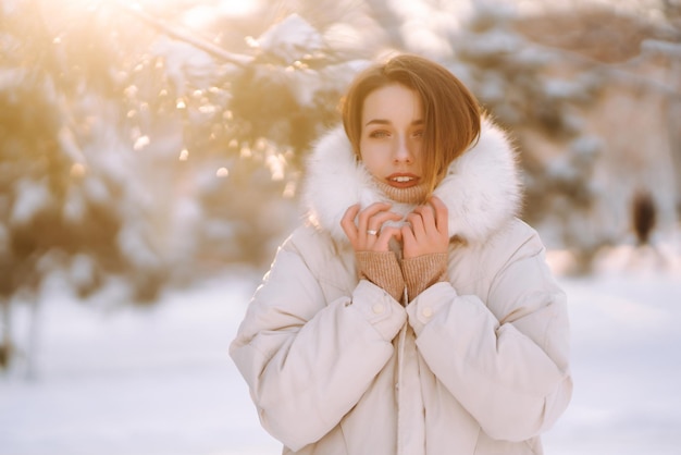 Beautiful woman in a snowy park. Young lady walking in a sunny winter day.