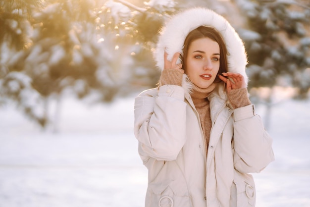 Beautiful woman in a snowy park. Young lady walking in a sunny winter day.