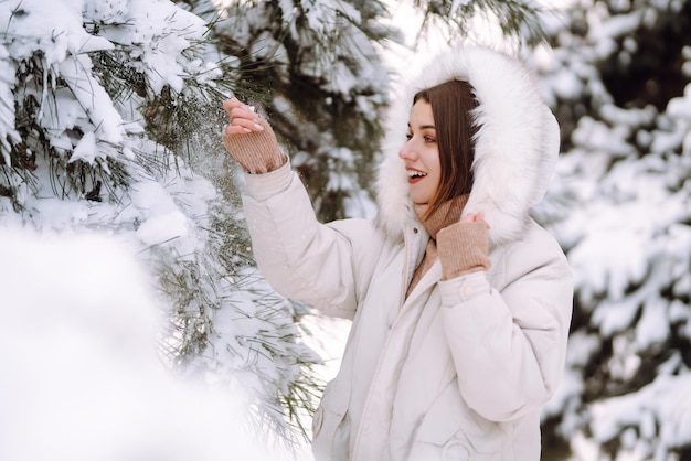 Beautiful woman in a snowy park. Young lady walking in a sunny winter day.