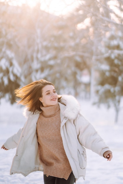 Beautiful woman in a snowy park Young lady walking in a sunny winter day