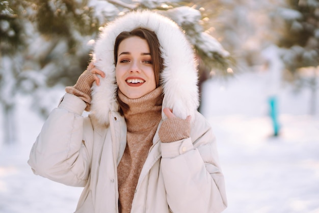 Beautiful woman in a snowy park Young lady walking in a sunny winter day