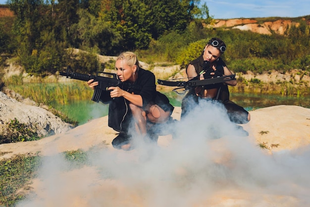 Beautiful woman soldier holding a rifle standing on a rock on the mountainblue sky hot sun