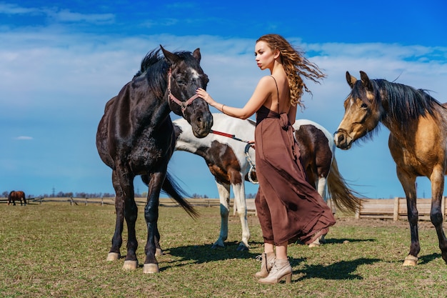 Beautiful woman standing in a field with a horse