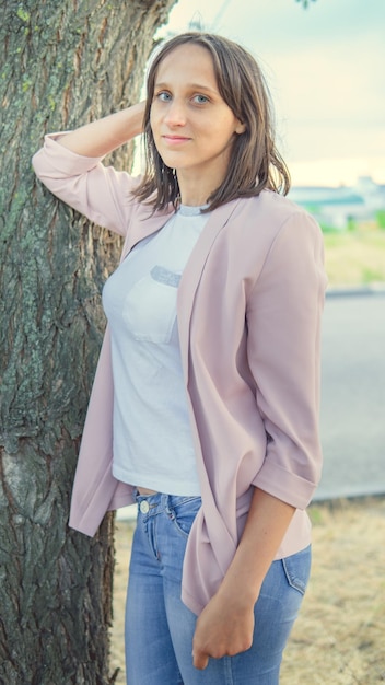 Beautiful woman standing near a tree and looking at the camera