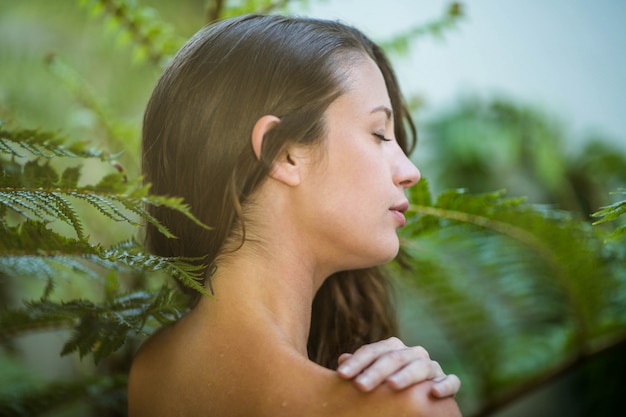 Beautiful woman standing outdoors against green plants