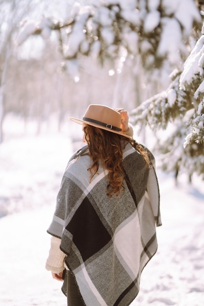 Beautiful woman standing among snowy trees and enjoying first snow. Happy time. Christmas.