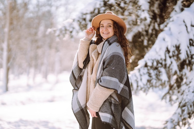 Beautiful woman standing among snowy trees and enjoying first snow. Happy time. Christmas.