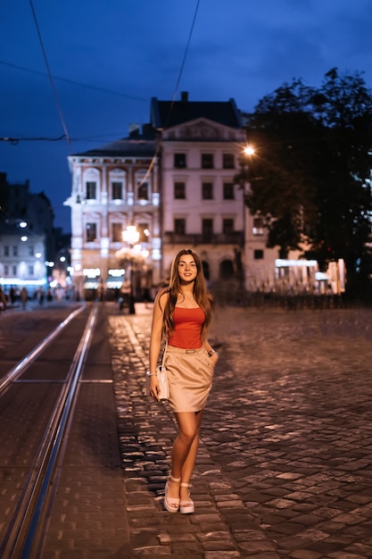 Beautiful woman standing on the square of an ancient evening city