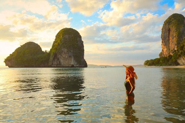 Beautiful woman standing in water during the sunset at tropical Railay Beach Krabi Thailand