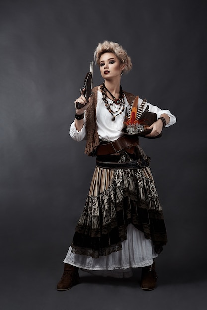 Beautiful woman in steampunk style costume with hat and handgun