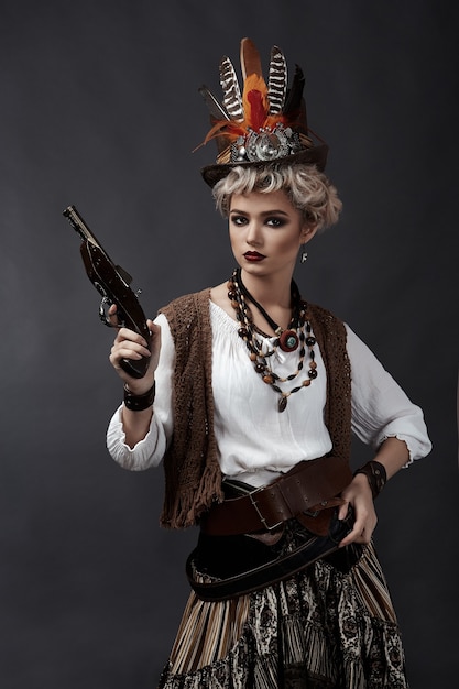 Beautiful woman in steampunk style costume with hat and handgun