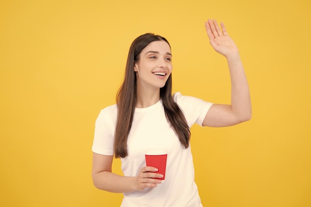 Beautiful woman in studio holding cup of coffee Photo of cheerful positive pretty girlf holding mug of coffee smiling toothily isolated over yellow background