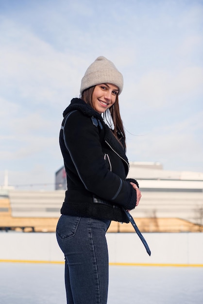 Beautiful woman at stylish jacket having fun laugh on outdoor ice skating rink Cheerful pretty young woman skate on Christmas ice rink Winter holiday outside activity