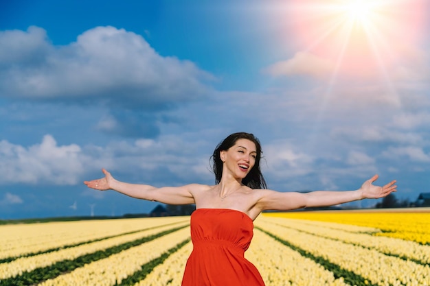 Beautiful woman in summer dres standing in colorful tulip flower fields in amsterdam region holland