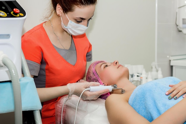 A beautiful woman takes a cosmetic procedure to improve the condition of the facial skin with microcurrents