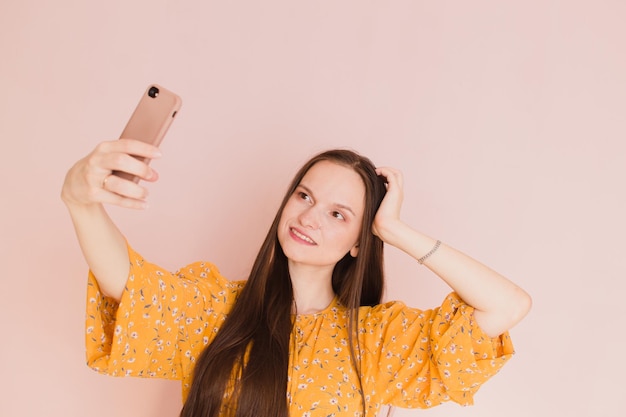 Beautiful woman taking selfie on pink background