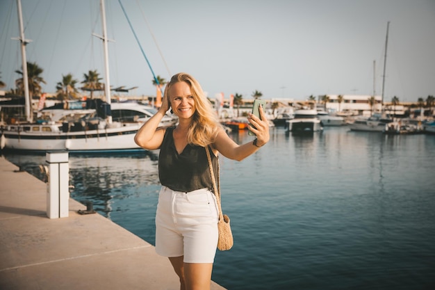 Beautiful woman in talking on the phone against the backdrop of the blue sea and yachts