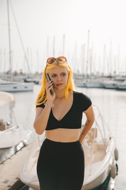 Beautiful woman in talking on the phone against the backdrop of the blue sea and yachts