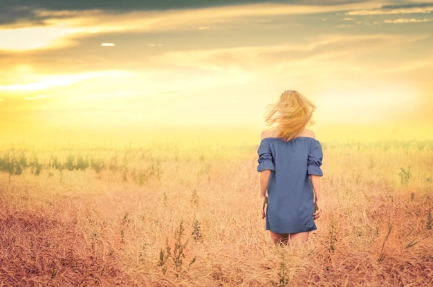 Beautiful woman walking in golden fields Woman in a wheat field Girl outdoors enjoying nature Empty place for text