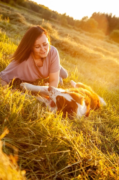 Beautiful woman walking out her dog in sunset field