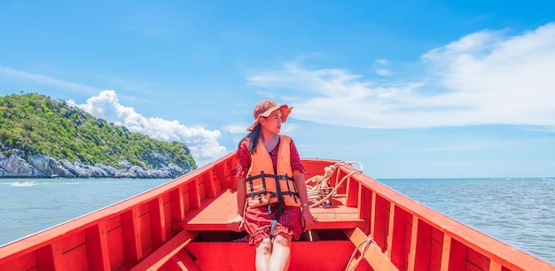 Beautiful woman wearing life jacket sits at the bow of the boat looking relaxed she travels alone