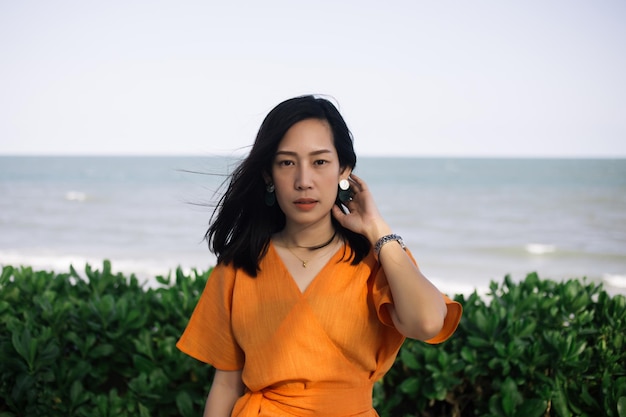 Beautiful woman wearing orange dress near beach