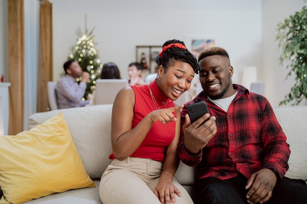 A beautiful woman wearing red top and man wearing plaid shirt are sitting on couch