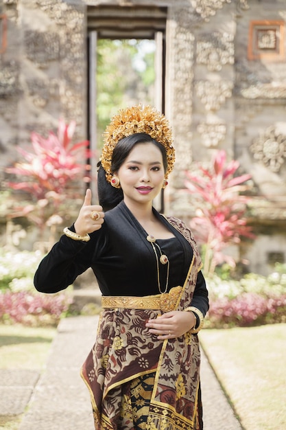 Beautiful woman wearing traditional balinese clothes standing with okay gesture