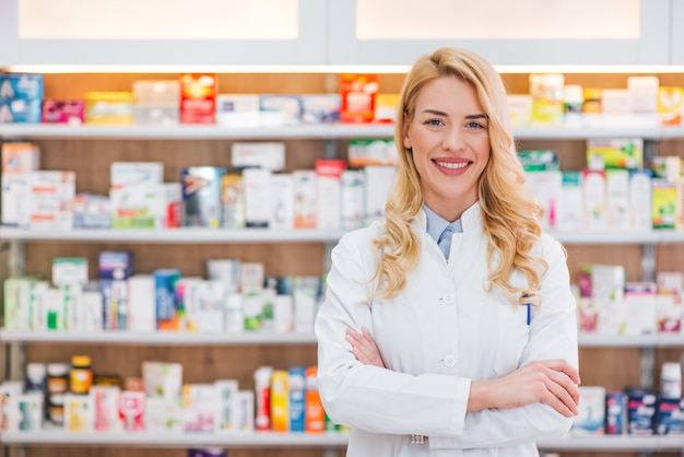 Beautiful woman wearing in white lab coat working in drugstore. 