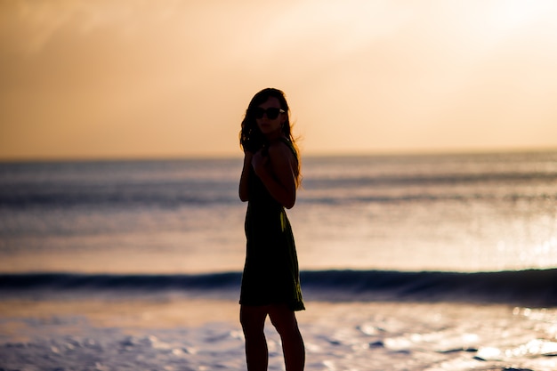 Beautiful woman on white beach at sunset.