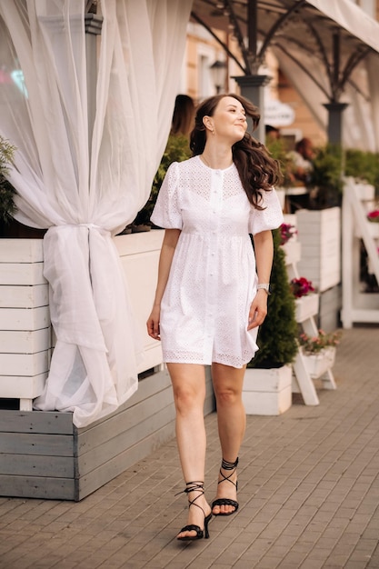 A beautiful woman in a white dress at sunset in the city Evening street photography