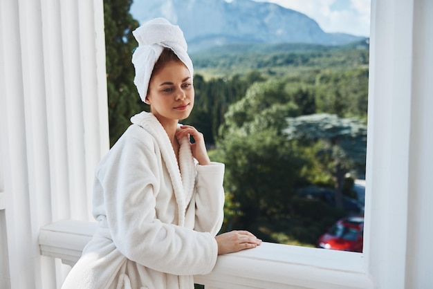 Photo beautiful woman in a white robe on the balcony bit on green nature perfect sunny morning high quality photo