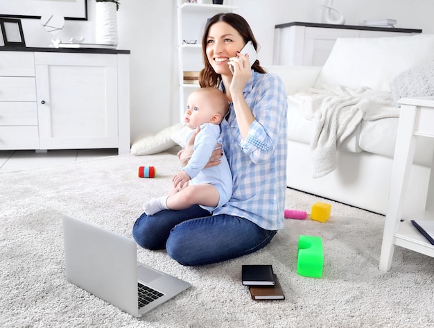 Beautiful woman with baby boy working from home using laptop