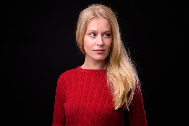  beautiful woman with blond hair wearing knitted sweater ready for winter against black wall