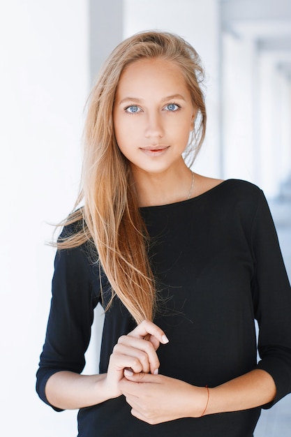 Beautiful woman with blue eyes in a black shirt on a light background