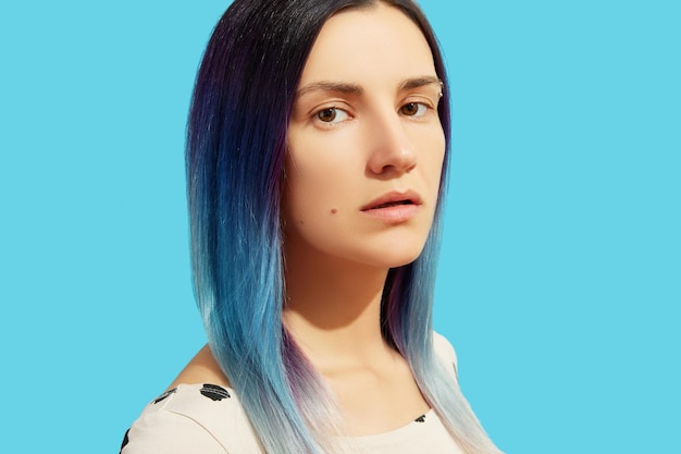 Beautiful woman with blue hair on bright background Girl standing looking at camera with copy space